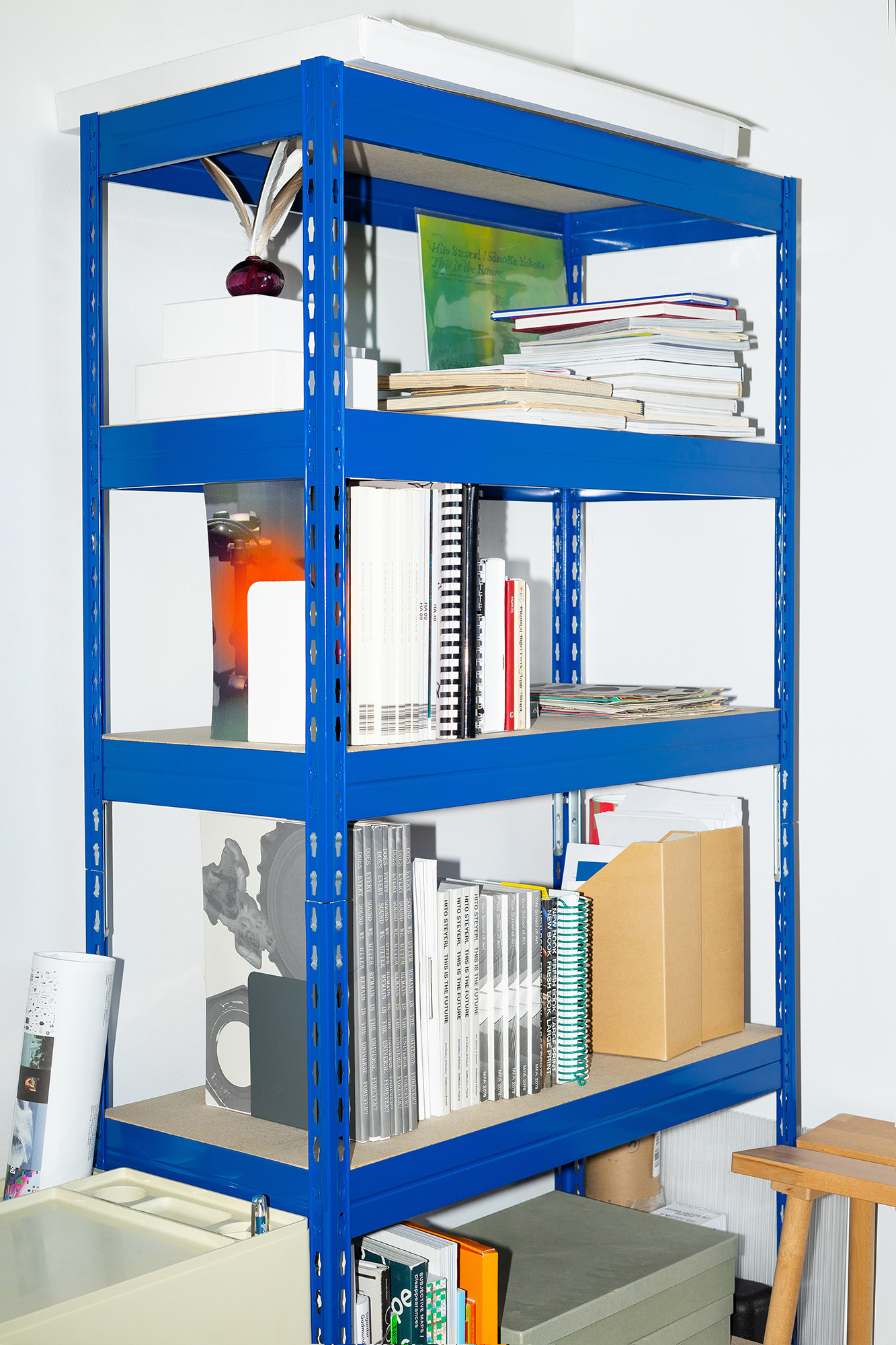 A blue industrial bookcase with various publications, papers and boxes.